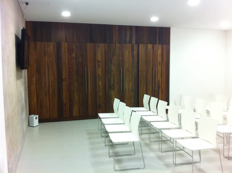 Sala de juntas con muro de madera y sillas blancas